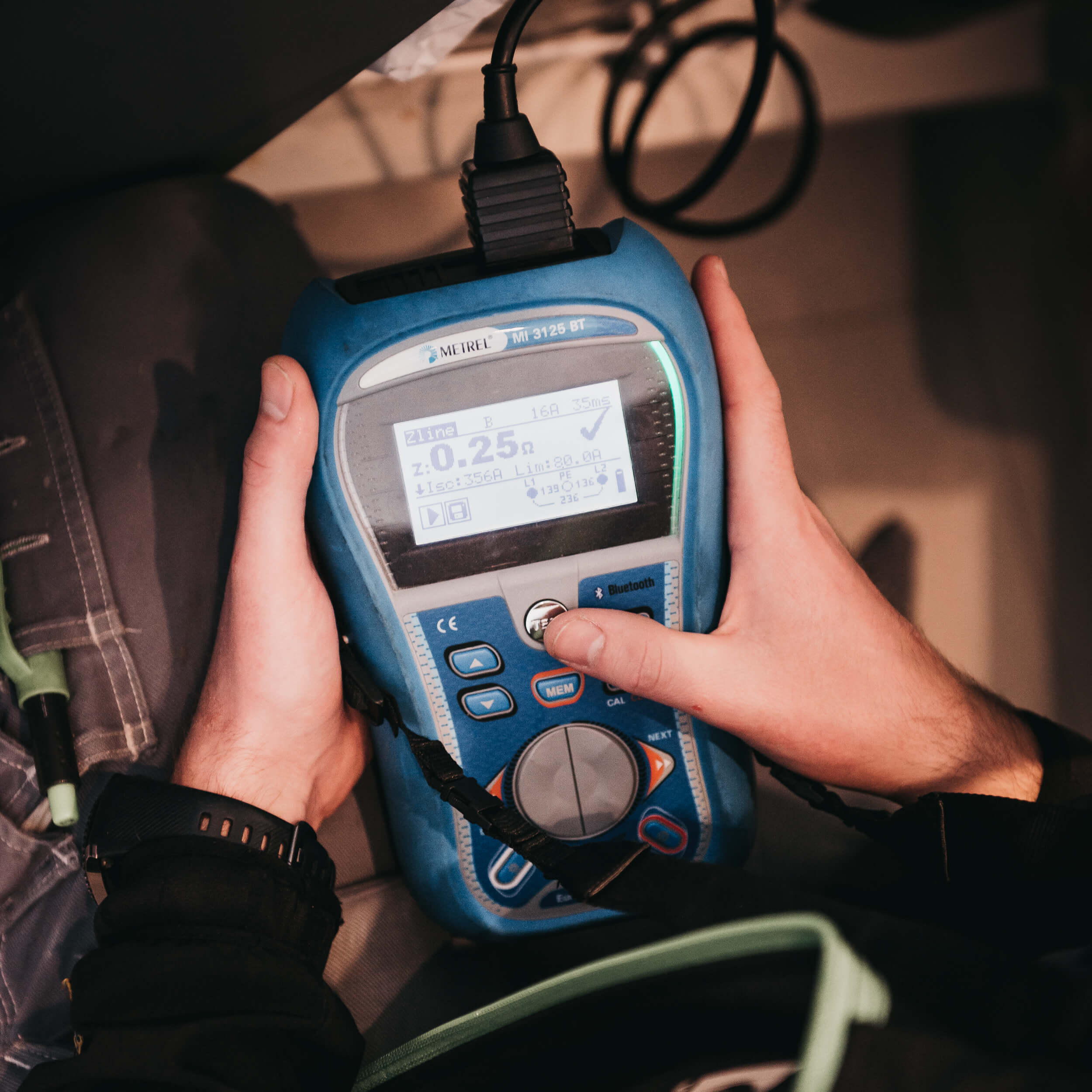 Elektriker bruker strøm-måler til å kontrollere stikkontakt.