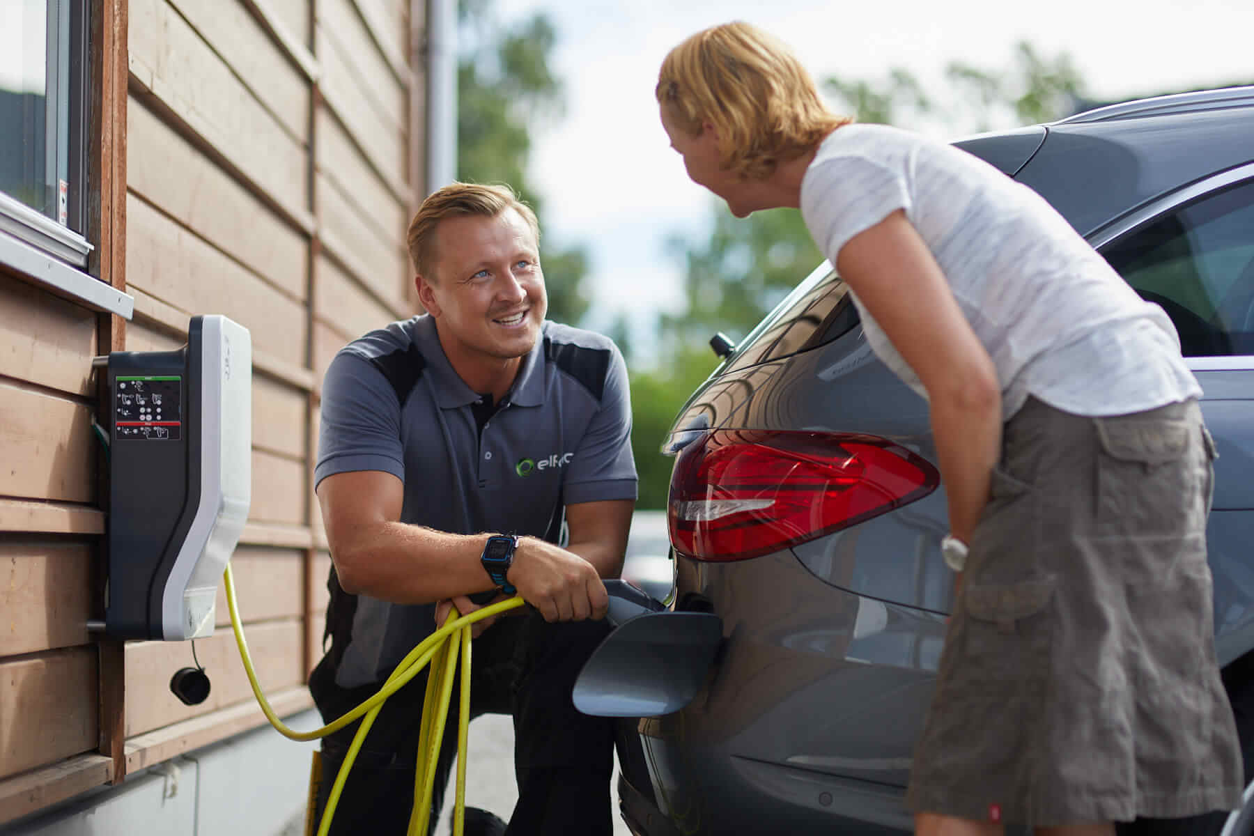Elfag elektriker og kunde med elbil-lader og bil.