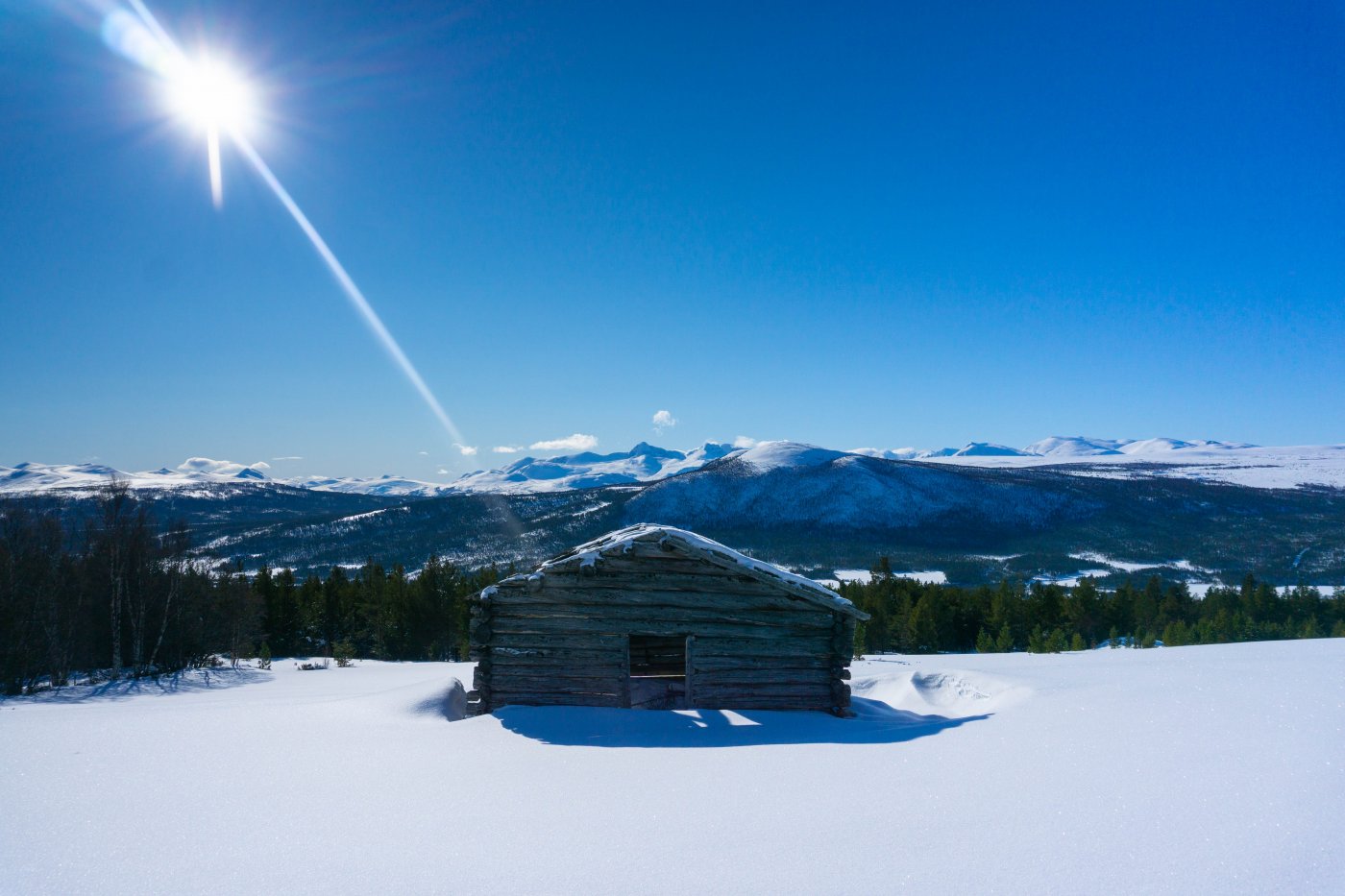 blå himmel, hvit snø og en liten urhytte i vinterlandskap