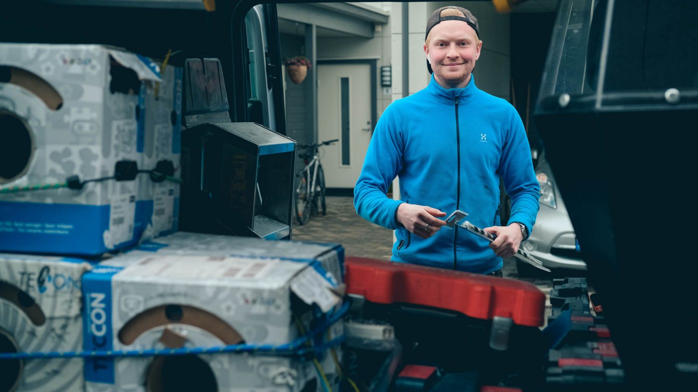 Elektriker Espen ser i kameraet mens han finner verktøy i arbeidsbilen.