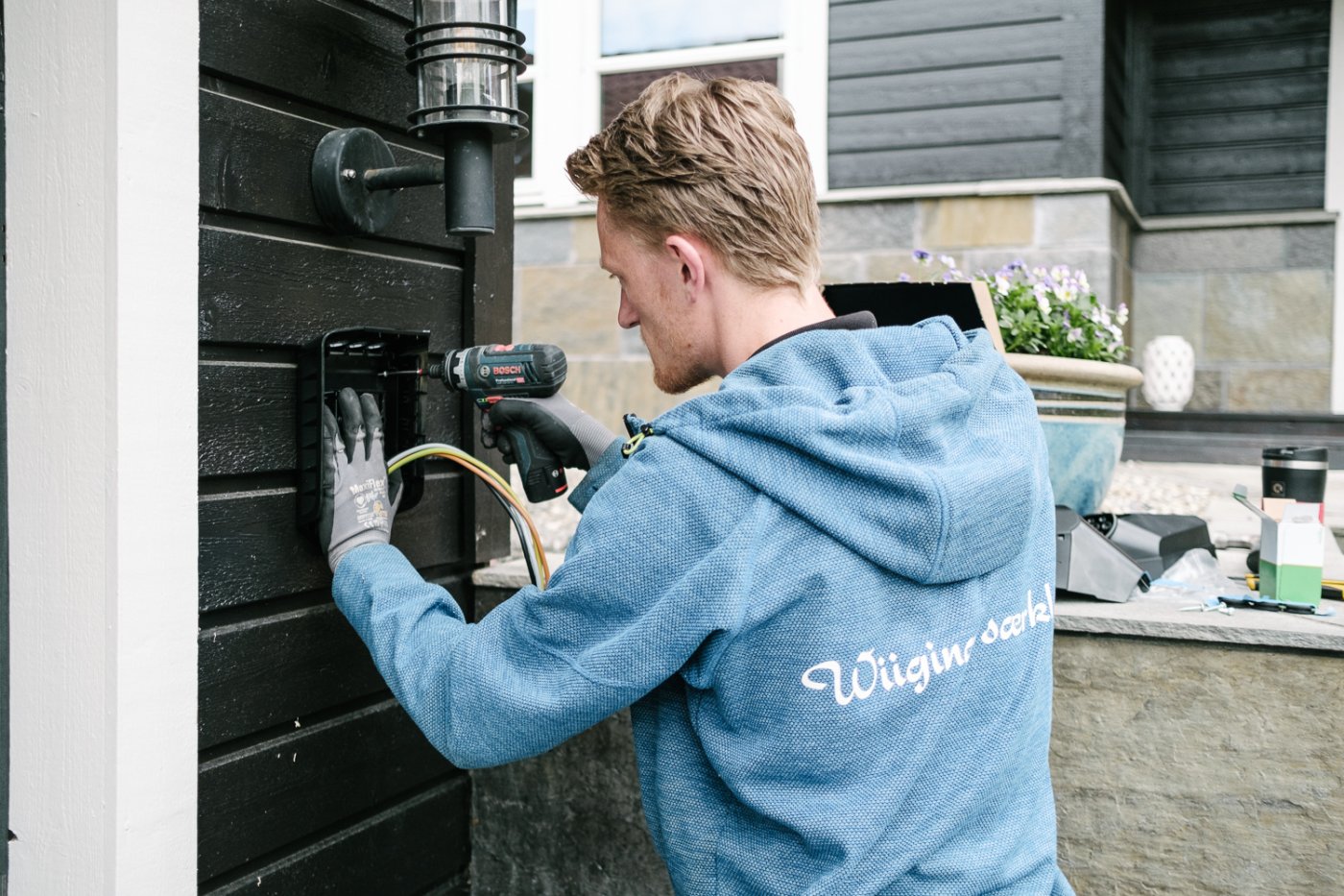 Elektriker Fredrik monterer Easee ladeboks på en garasjevegg.