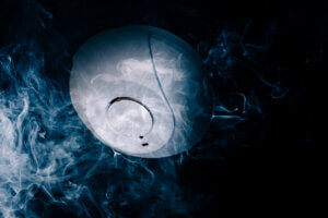 Hvit røyk foran en røykvarsler i et mørkt rom