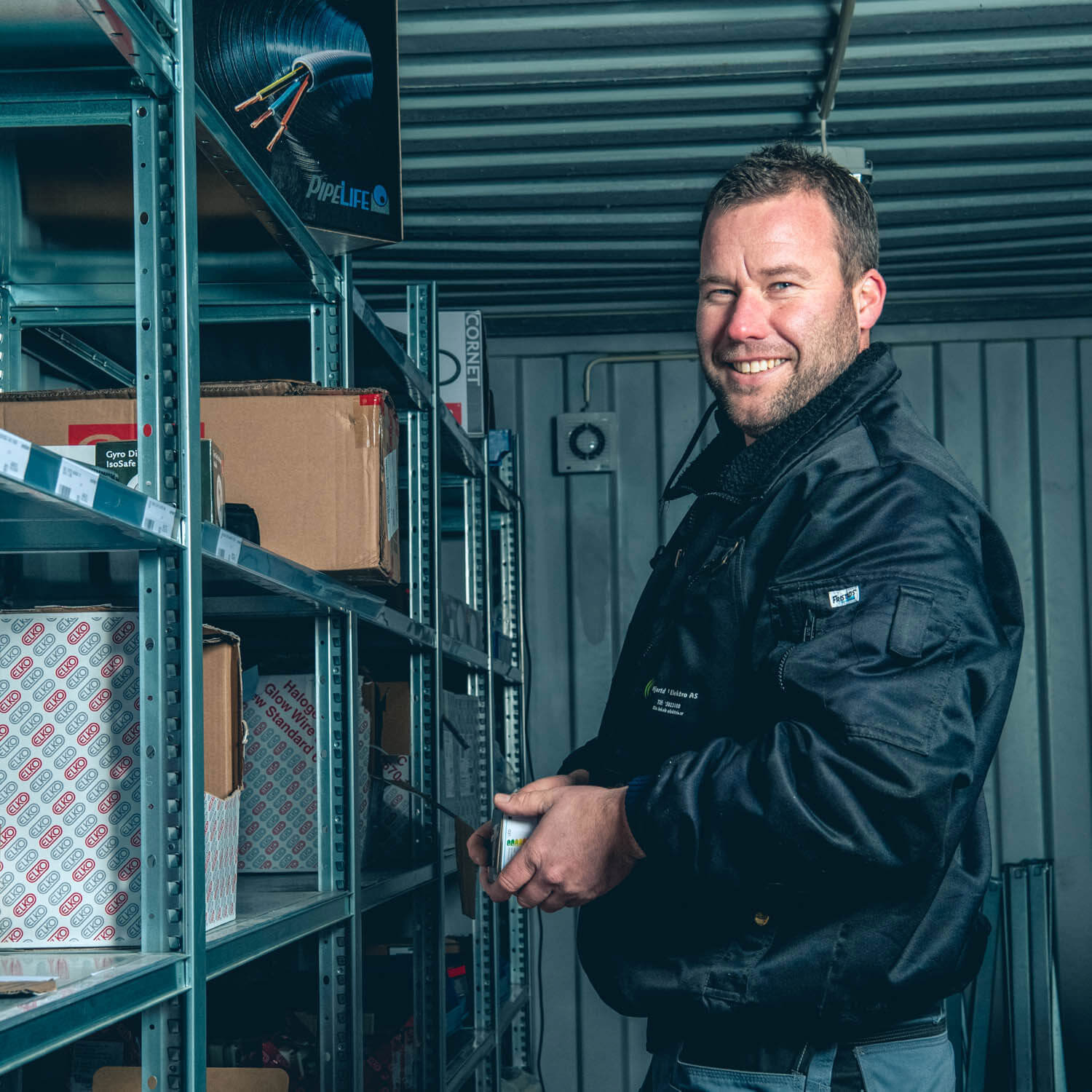 Daglig leder i Hjartdal Elektro, Øyvind Hovde Kaasa, smiler mot kamera fra innsiden av et VMI-lager.
