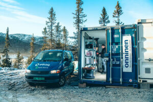 En bil med Elfag-logo står parkert ved siden av et VMI-lager i en container på en byggeplass.