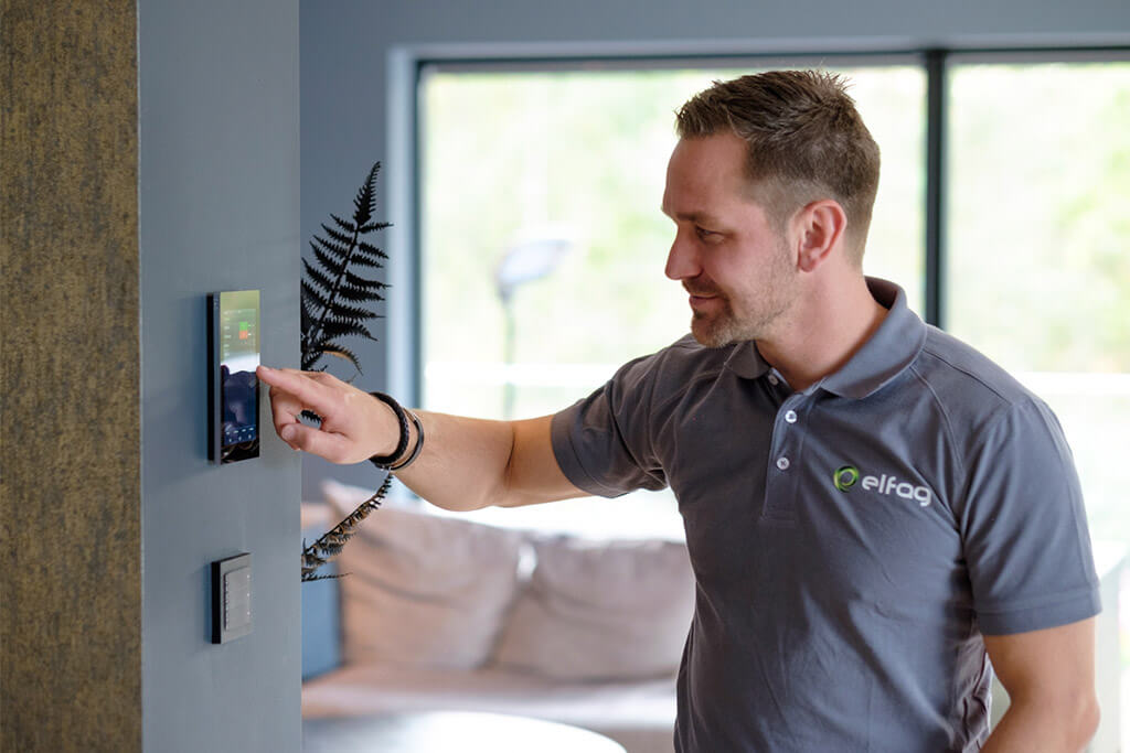 En elektriker stiller inn termostaten som er festet på veggen