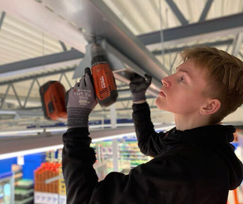 Lærking som skrur ut skruer med elektrisk drill.