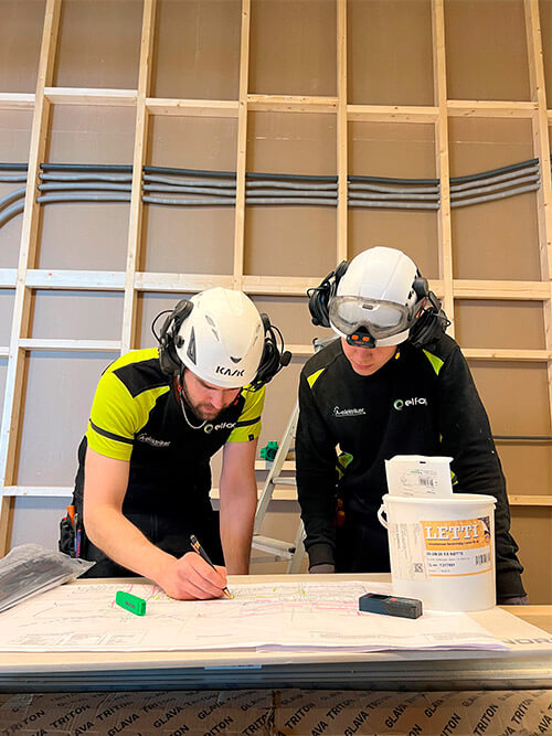 To elektrikere står bøyd over ark