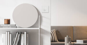 ELKO Plus-dimmer i renhvit på en lys vegg mellom en bokhylle og en grå sofa i en moderne stue.